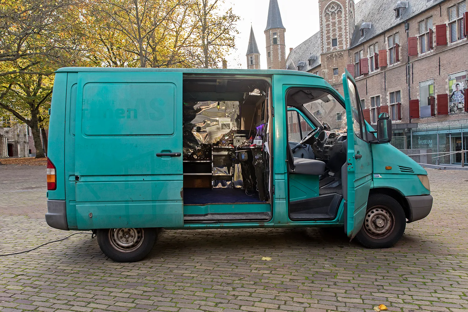 Turquoise van with doors open, parked in the middle of a square in Middelburg