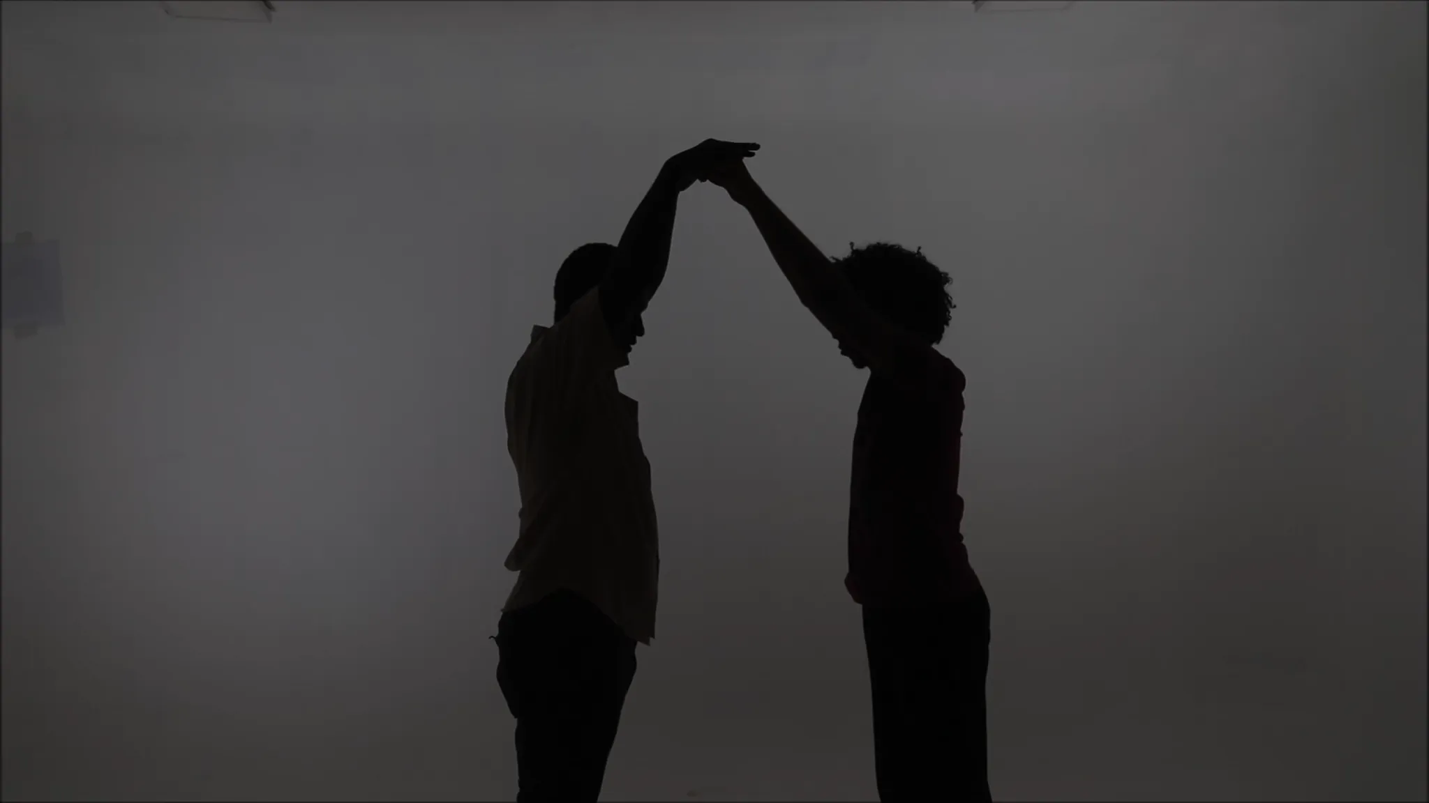 Zwarte schaduwen van twee personen die elkaars handen vasthouden, armen omhoog