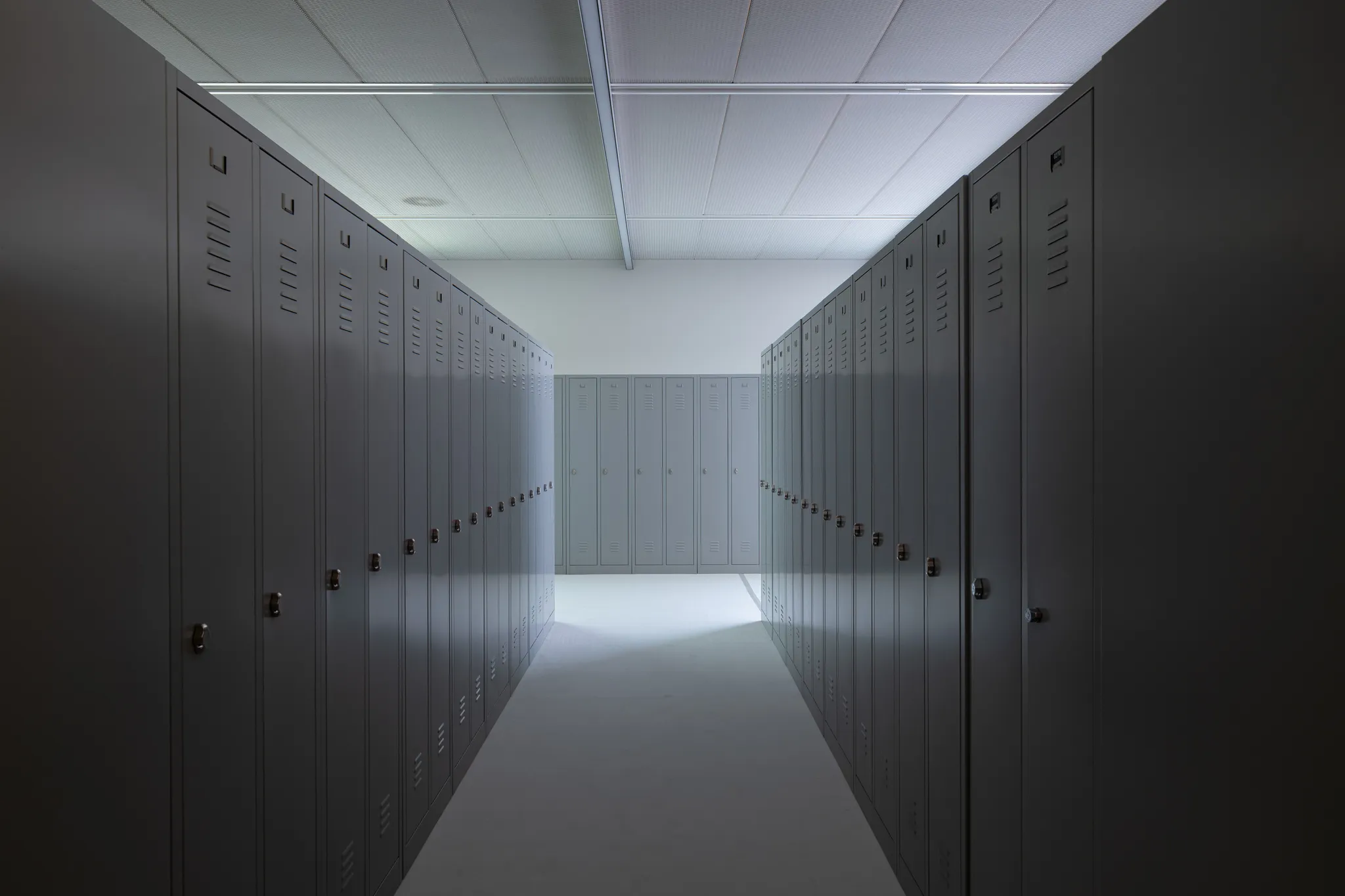 Rijen grijze metalen schoolkluisjes in schemerig licht