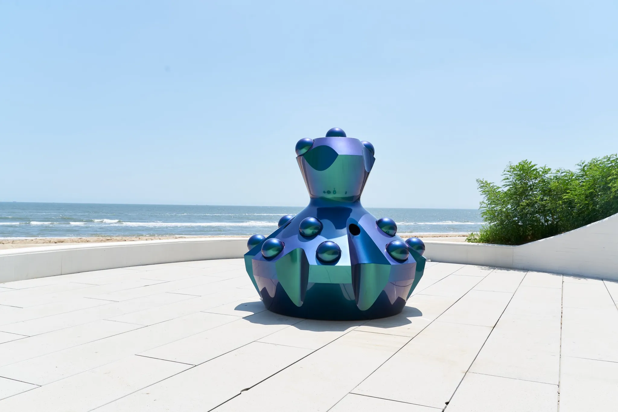 Een iriserend gekleurd beeld op een betegeld terras aan het strand