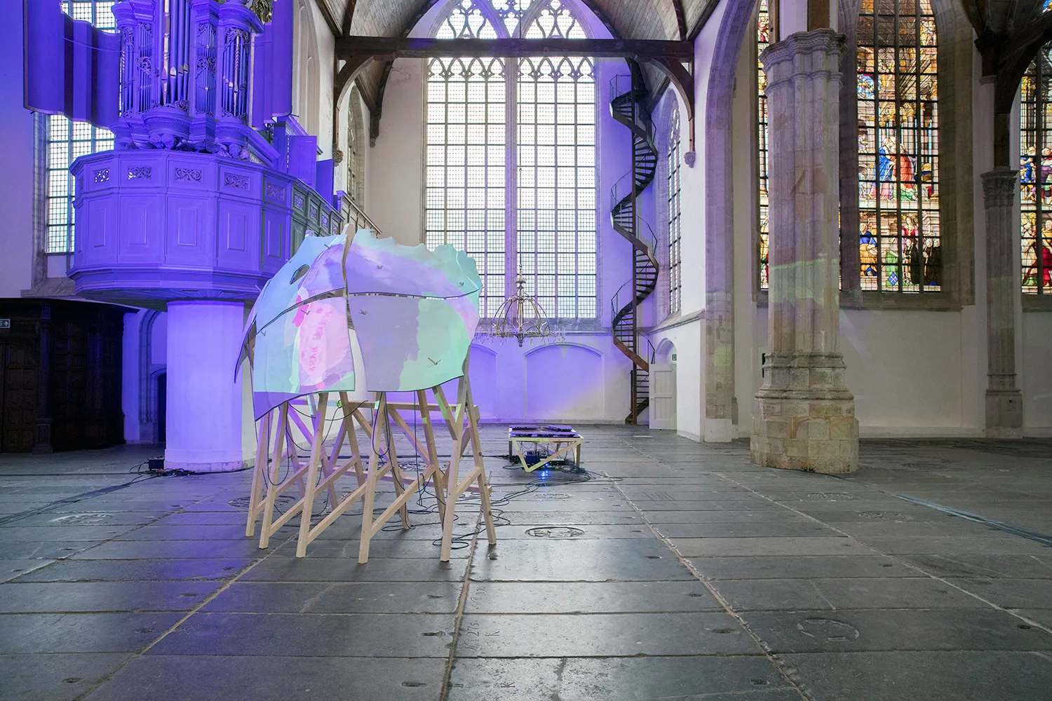 Blue/ green/ purple projection onto a sculptural piece placed inside the Old Church of Amsterdam
