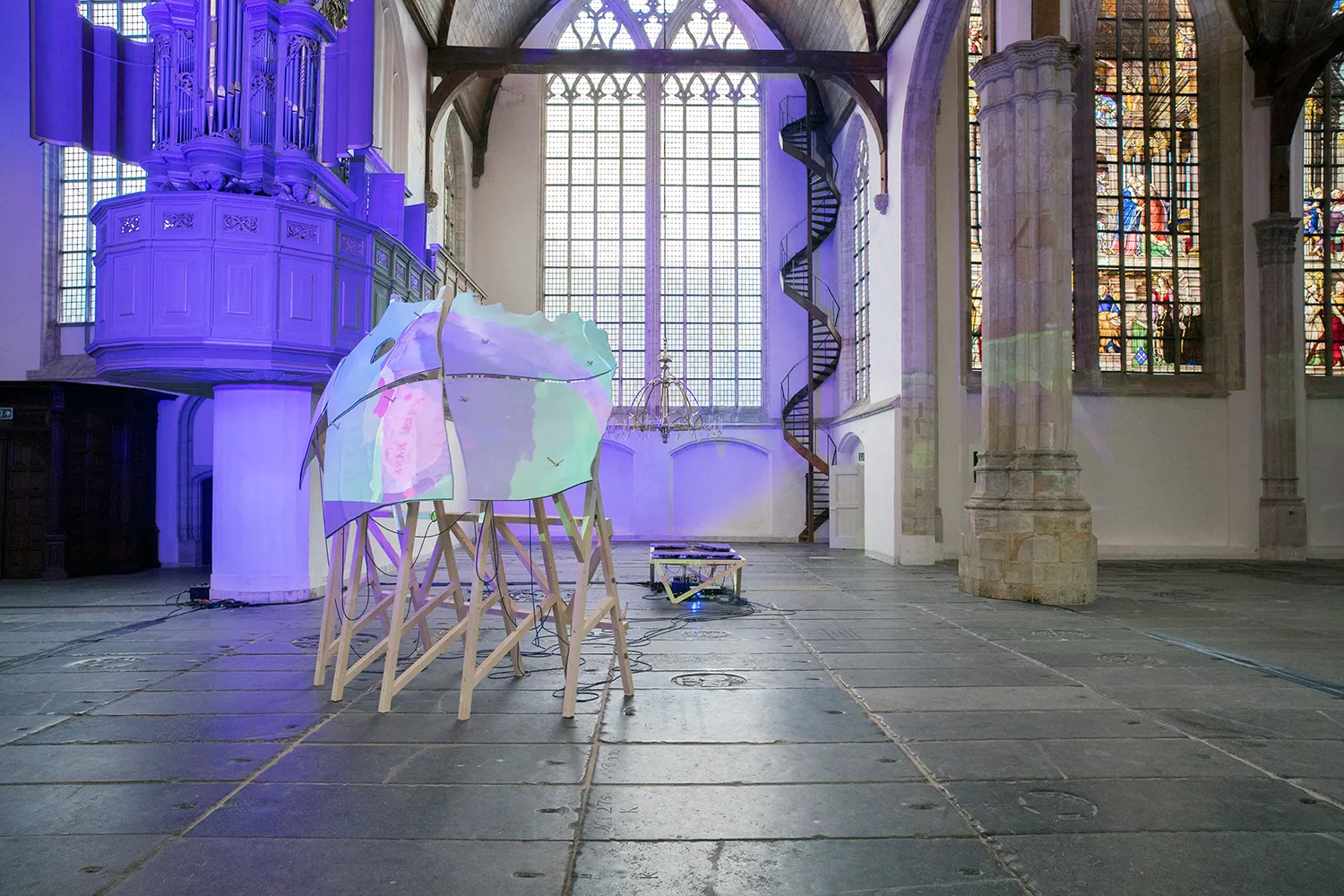 Blauw/groen/paarse projectie op een sculptuur in de Oude Kerk van Amsterdam.