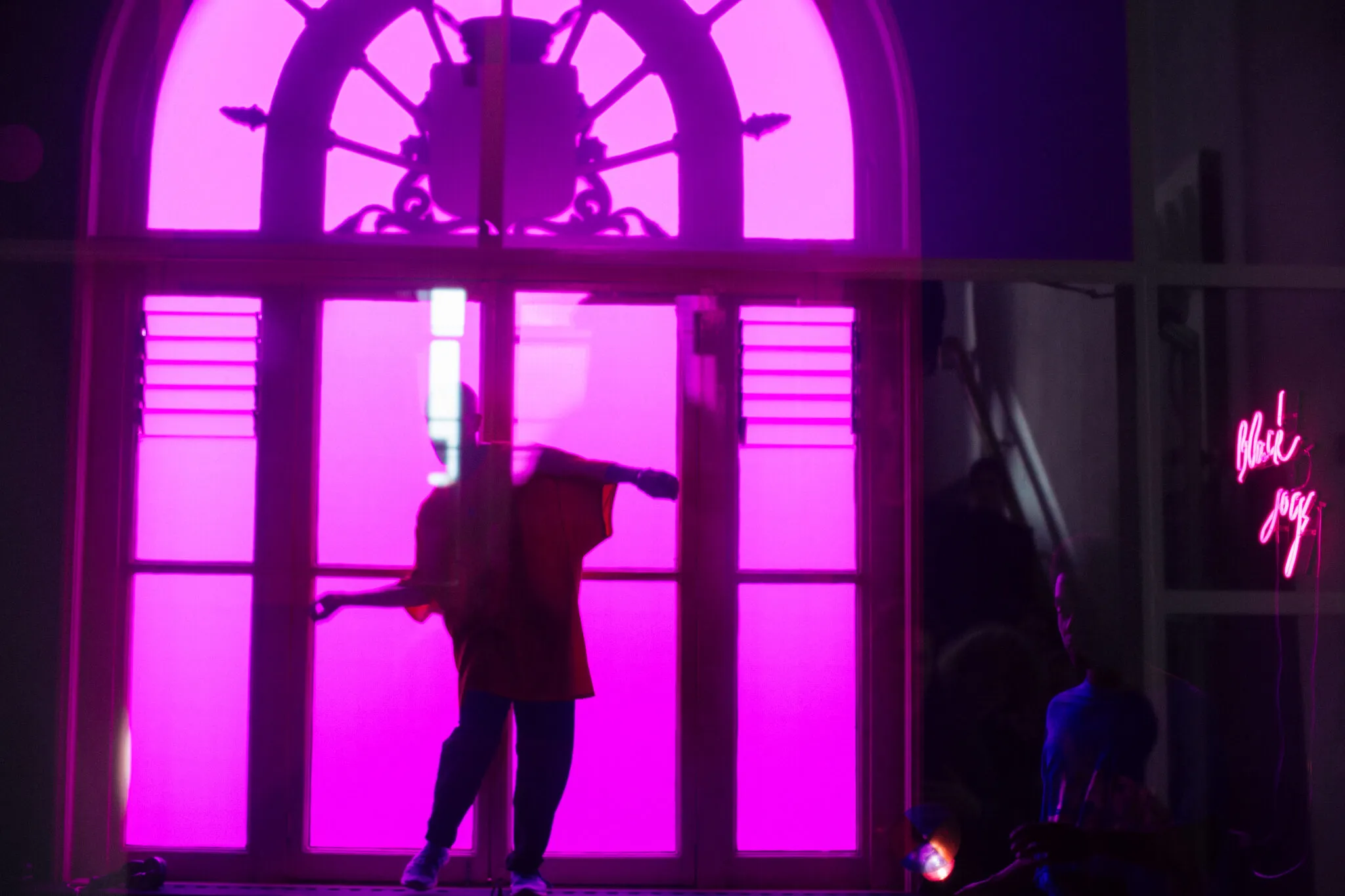 A performer dancing on a window ledge, photographed through a purple glass