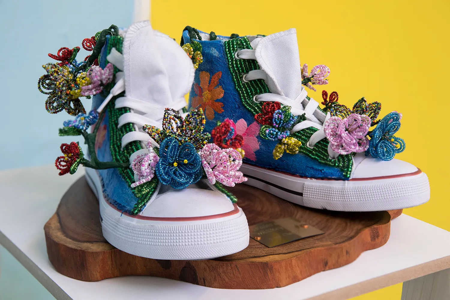 High-top blauwe sneakers met witte zolen, versierd met kralenbloemen