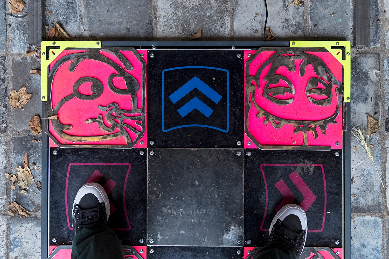 The feet of the photographer on the dancepad with red cartoonish faces