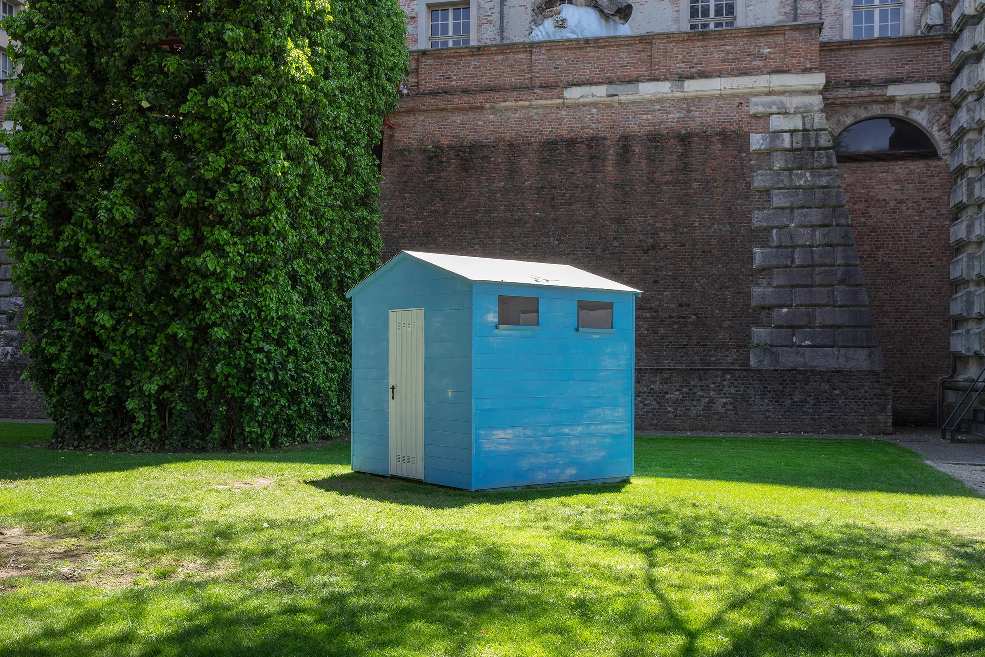 Een blauwe houten strandhut op een zonnig groen gazon