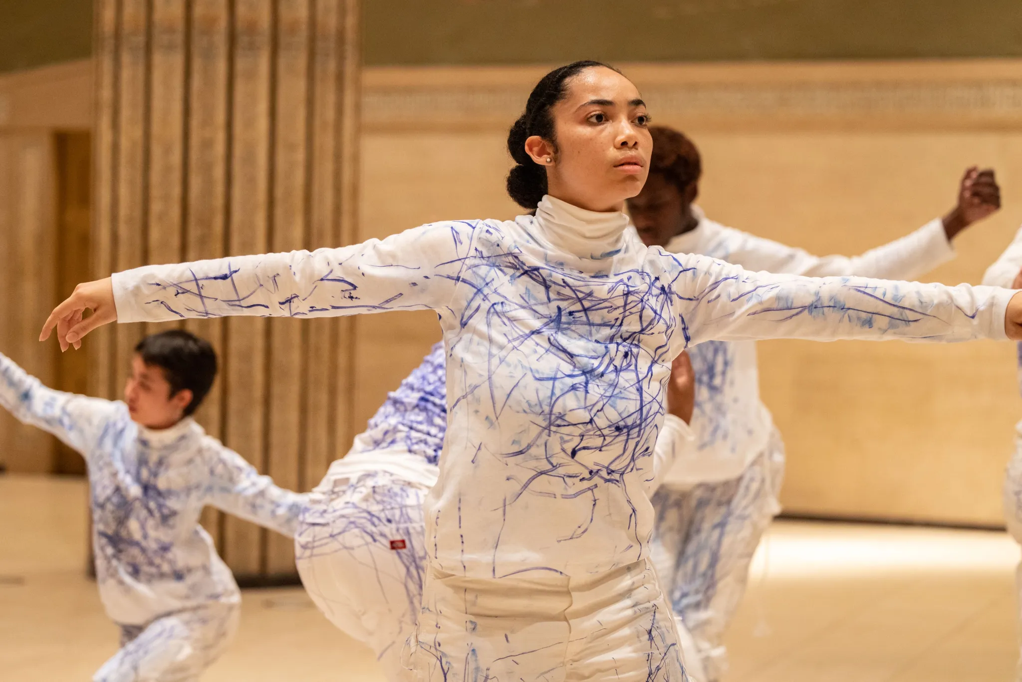 Focused performer with outstretched arm, surrounded by fellow performers in the background.