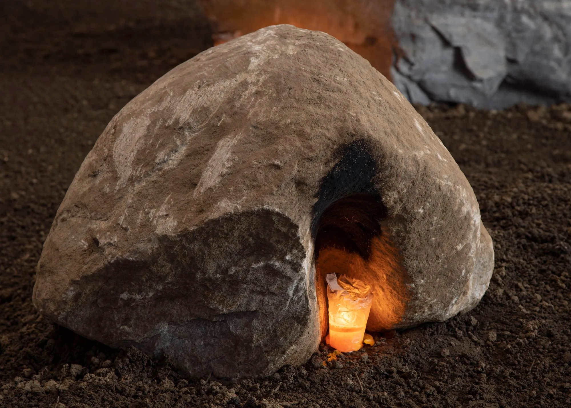 Close up of the installation, a peach-shaped rock with a burning candle