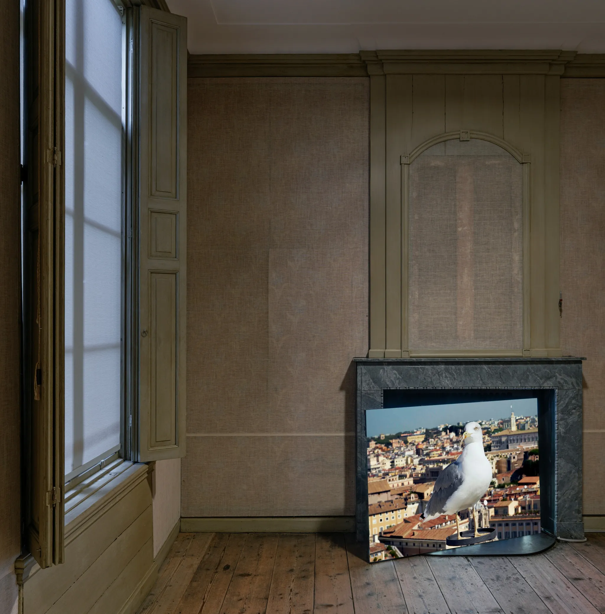The image of a seagull perched on top of a building, on a screen placed diagonally in front of a marble chimney