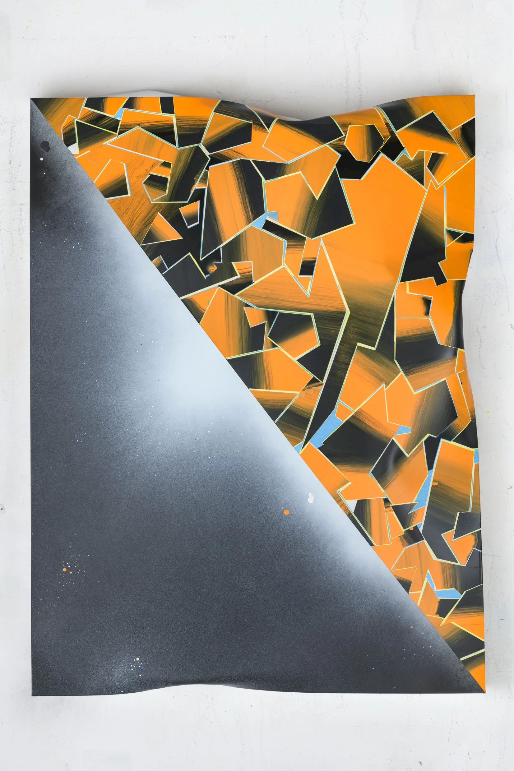 A dented, sculptural metal plate featuring a diagonal division, with a black-to-white gradient on one side and predominantly orange geometric shapes on the other.